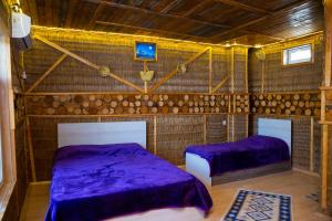 two beds in a room with purple sheets at Baku "Black Mountain" Guest House in Sangachal