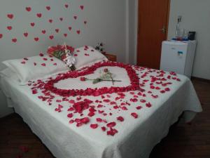 a bed covered in red roses with a heart on it at Pousada Santa Mônica in Divinópolis