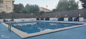a swimming pool with white chairs and tables and chairs at Apartamentos Cala Azul La Móra in Tarragona