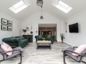 a living room with green furniture and a flat screen tv at Ty Coch in Ruthin