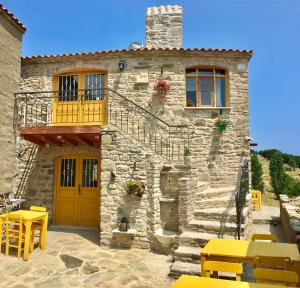 a stone house with yellow tables and chairs in front of it at SARI KEÇİ TAŞ OTEL in Gokceada Town