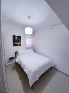 a white bedroom with a large white bed with a chandelier at Royal House in Eilat