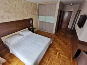 een slaapkamer met een wit bed en een houten vloer bij Villa Salvia in Mostar