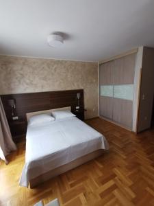 a bedroom with a large white bed and wooden floors at Villa Salvia in Mostar