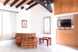 a living room with a chair and a flat screen tv at La Capilla Hotel in Dolores Hidalgo