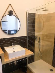Un baño con lavabo y ducha con espejo. en BAIA BLU APARTMENTS, en Muggiano