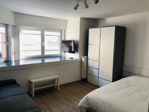 a bedroom with a bed and two windows and a refrigerator at Studio close from train station and shops in Luxembourg +4 photos