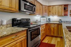 una cocina con armarios de madera y electrodomésticos de acero inoxidable en The Pines at Ore House 304 PH4 en Steamboat Springs