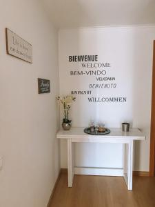 una mesa blanca en una habitación con palabras en la pared en Beach House Carmen, en Monte Gordo