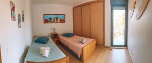 Una pequeña habitación con dos camas y una ventana. en Beach House Carmen, en Monte Gordo