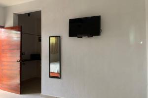 a flat screen tv on a wall with a mirror at Baona Bacalar in Bacalar