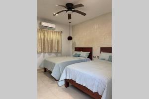 a bedroom with two beds and a ceiling fan at Baona Bacalar in Bacalar