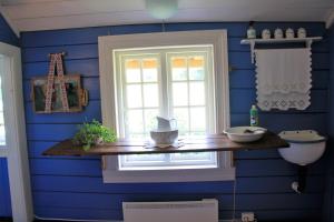 a blue bathroom with a window and a wooden shelf at Lille Gjersdal - Et unikt opphold 100 år tilbake i tid in Farsund