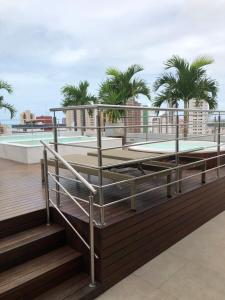 a rooftop deck with a pool and palm trees at Manaíra Apart Hotel - Flat 201 in João Pessoa