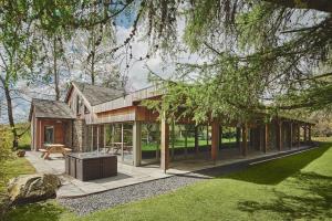 a house with glass walls and a patio at The Shippon Cottage in Kendal