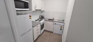 a kitchen with a stove, microwave, and refrigerator at Chasely Apartment Hotel in Brisbane