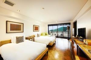 熱海市にある熱海温泉リラックスリゾートホテルのベッド2台とテレビがあるホテルの部屋