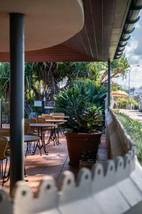 a patio with tables and chairs and potted plants at Beach Hotel Resort in Byron Bay
