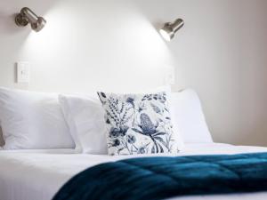 a bed with a blue blanket and a pillow on it at Drovers Motor Inn in Palmerston North
