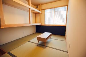 een kleine kamer met een bank en een raam bij ゲストハウス酒坊多満自慢 in Fussa