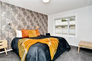 クライストチャーチにあるBrockworth Place - Christchurch Holiday Homesのベッドルーム1室(大型ベッド1台、オレンジ色の枕付)
