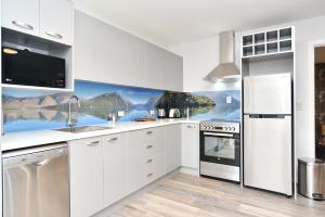 クライストチャーチにあるBrockworth Place - Christchurch Holiday Homesの白いキャビネットと壁画が備わるキッチン