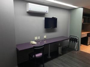 a desk with a phone and a tv on a wall at Grand Mercure Brasília - Ap Particular 112 in Brasilia