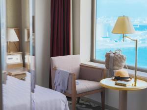 une chambre d'hôtel avec une chaise, une table et une fenêtre dans l'établissement Surfeel Hotel Wakkanai, à Wakkanai