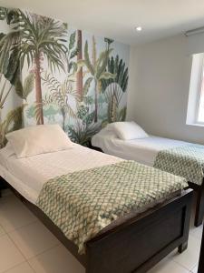 2 camas en un dormitorio con papel pintado tropical en Tropical Breeze Apartamentos en San Andrés