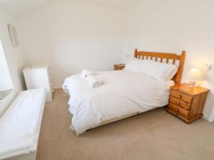 a bedroom with a white bed and a night stand with a lamp at Rosewall Cottage in St Ives