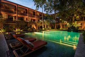 a swimming pool with lounge chairs in front of a building at Andaz Bali, By Hyatt in Sanur
