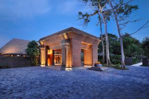 a house with a stone facade with a tree at Andaz Bali, By Hyatt in Sanur
