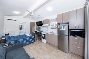 a kitchen with a refrigerator, stove, sink and a television at Kingaroy Holiday Park in Kingaroy