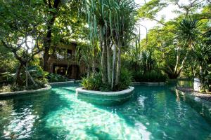 a pool in a garden with a palm tree at Andaz Bali, By Hyatt in Sanur
