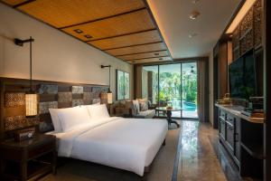 a bedroom with a large white bed and a living room at Andaz Bali, By Hyatt in Sanur