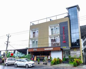 a building with two cars parked in front of it at Hillfort Inn in Sultan Bathery