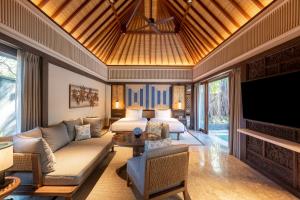 a living room with a couch and a bed and a television at Andaz Bali, By Hyatt in Sanur