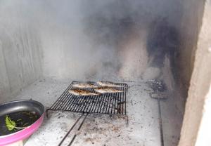 um grill com alguma comida cozinhando em cima dele em Holiday home Dusko - robinson em Zirje