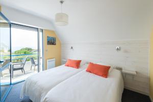 - une chambre avec un lit doté d'oreillers orange et un balcon dans l'établissement Appartement face à l'Océan- Penhors, à Pouldreuzic