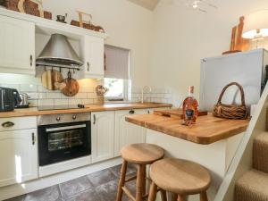 a kitchen with white cabinets and a counter with stools at Gable End in High Yewdale
