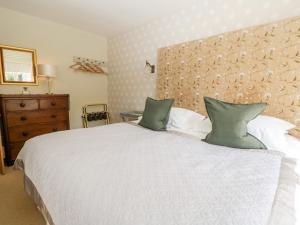 una camera con un letto bianco con due cuscini verdi di Gable End a High Yewdale