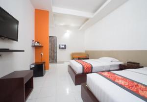 a hotel room with two beds and a flat screen tv at Adikara Renon in Denpasar