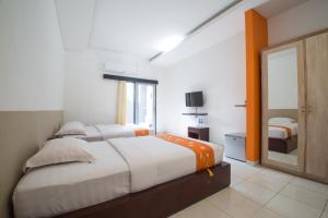 a bedroom with two beds and a mirror at Adikara Renon in Denpasar