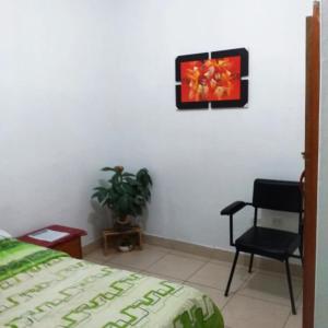 a bedroom with a chair and a picture on the wall at Backpacker Kitara House in Tarapoto