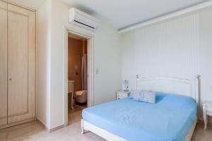 a white bedroom with a blue bed and a bathroom at Villa Nostalgia Lentas No4 in Lentas
