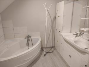 ein weißes Badezimmer mit einer Badewanne und einem Waschbecken in der Unterkunft Maison proche gare avec extérieur in Neufchâteau