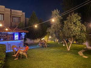 Una donna seduta a un tavolo in un giardino di notte di Sunrise Aya Hotel a Pamukkale