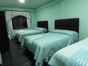 three beds in a room with blue walls at Hostal El Paraiso in Tarija