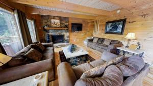 un soggiorno con divani e camino in una baita di tronchi di Bearly Hidden Ridge Cabin a Gatlinburg