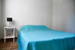 a bedroom with a bed with a blue blanket and a table at Departamentos Victoria in Paraná